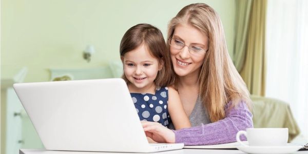 Mother and daughter happily using a laptop together.