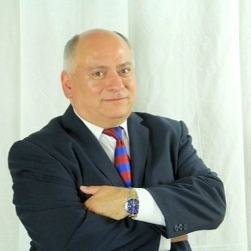 Man in a suit with arms crossed, smiling at the camera.