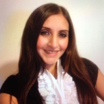 A young woman with long brown hair smiling at the camera.