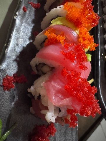 Close-up of sushi roll topped with red and orange fish roe.
