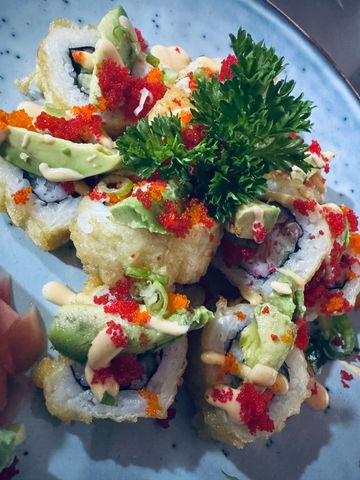 A plate of colorful sushi rolls garnished with avocado, fish roe, and parsley.