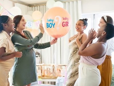 Shot of a group of women about to pop a balloon for a gender reveal during a baby shower.