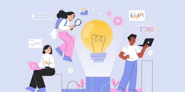 People collaborating with technology around a giant illuminated light bulb symbolizing ideas.