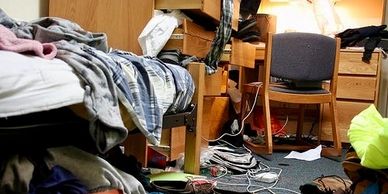 Messy dorm room with clothes and shoes scattered.