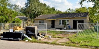 House with discarded furniture in front yard.
