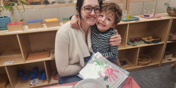 Mother and child happily hugging at a table.