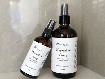 Two brown bottles of Finn & Jax Magnesium Spray on a light surface.
