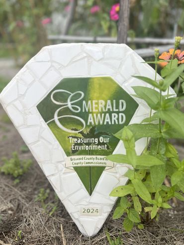 Emerald Award plaque in a garden honoring environmental efforts in 2024.