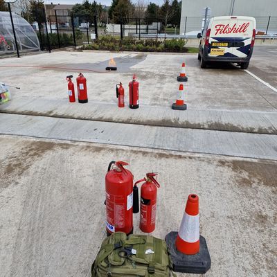 Fire safety training setup with fire extinguishers and cones.