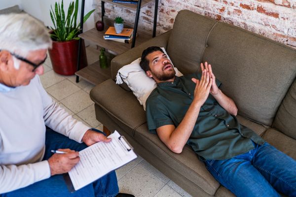 Young patient man talking to psychotherapist during therapy session at clinic
