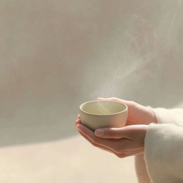 Hands gently holding a steaming cup in soft natural light.