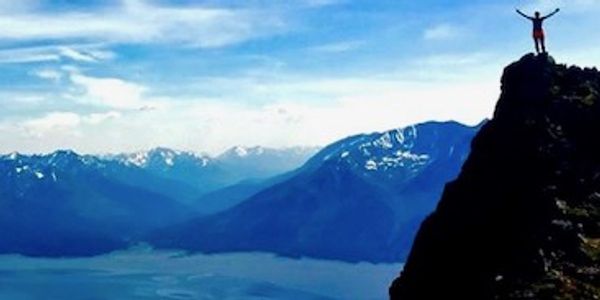 Person standing triumphantly on a mountain peak.