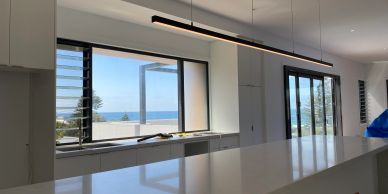 Modern kitchen with ocean view and large windows.