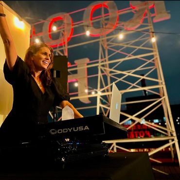 A woman djing in front of a sign