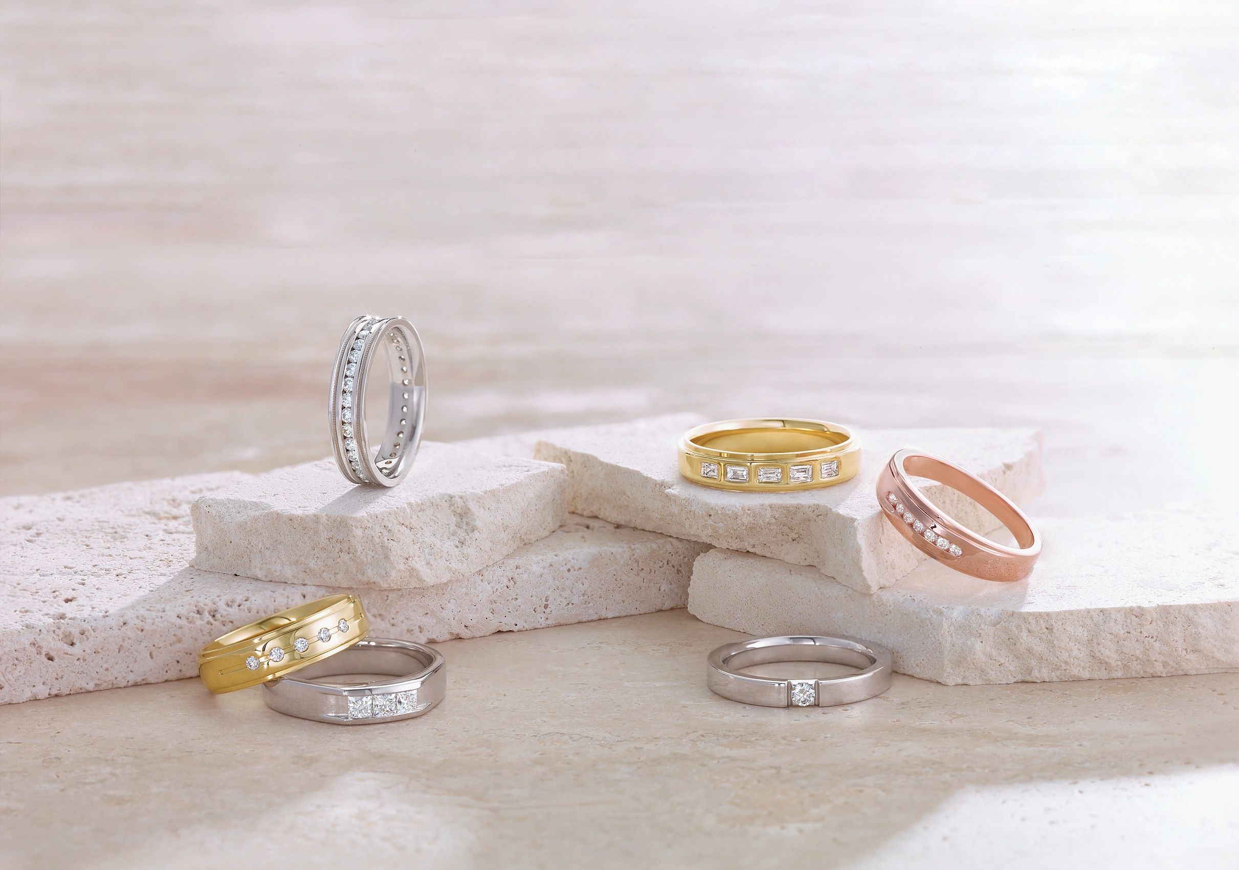 Collection of gold, rose gold, and white gold wedding bands with diamond accents.