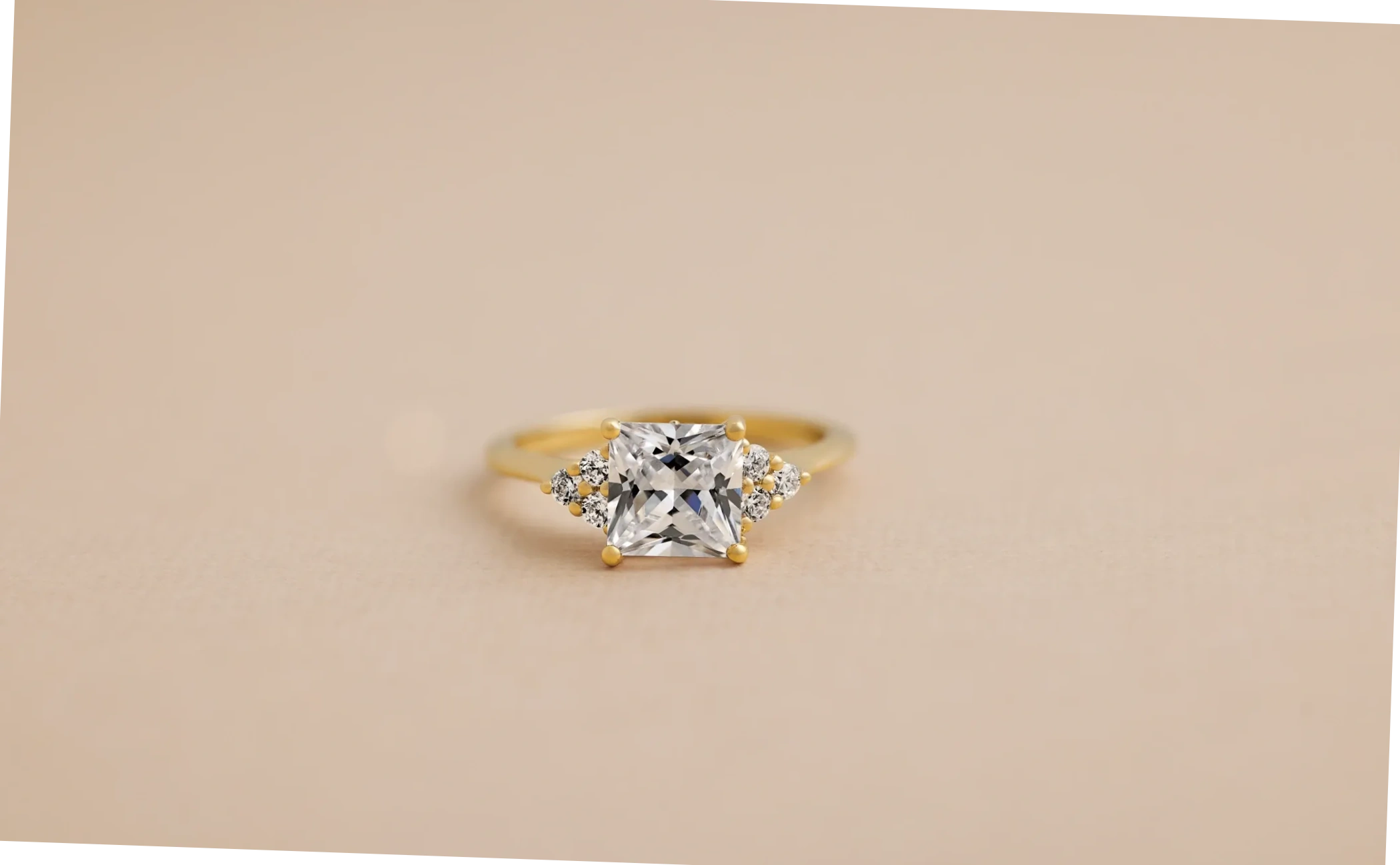 Gold engagement ring with a square lab-grown diamond and smaller diamond accents.
