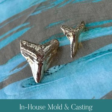 Two metal shark-tooth castings created from the original mold.
