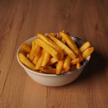 A bowl filled with golden French fries on a wooden table.