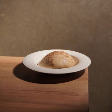 A dome-shaped dessert dusted with cocoa on a white plate.