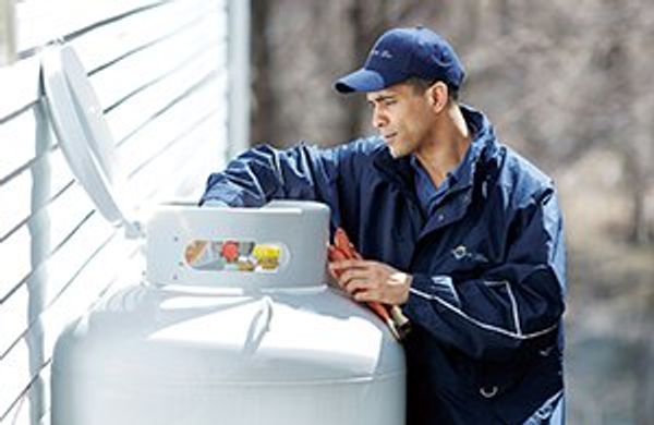 Technician inspecting a propane tank outside a house.