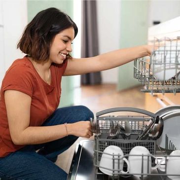 woman smiling while unloading dishwasher