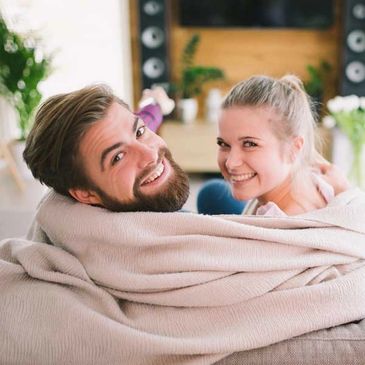 a young couple wrapped in a blanket smiling at the camera