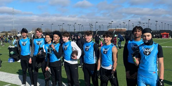 A group of young athletes in blue sportswear posing on a football field.