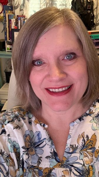 Smiling woman with short hair in a cozy home office setting.