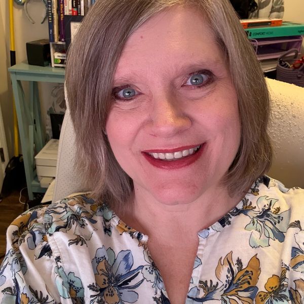 Smiling woman with short hair in a cozy home office setting.