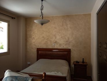 A simple bedroom with a wooden bed and nightstand under a ceiling light.