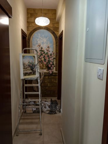 Hallway mural painting in progress with a ladder and floral artwork.