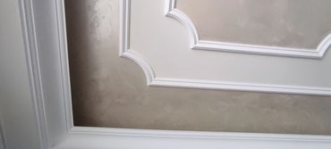 Decorative ceiling with textured beige paint and white molding.