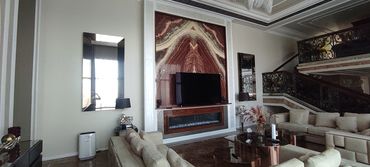 Luxurious living room with beige sofas, a large TV, and elegant decorative mirrors.