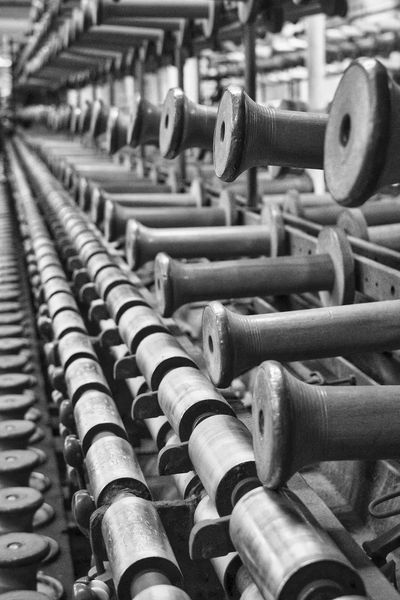 Rows of empty wooden spools in black and white.
