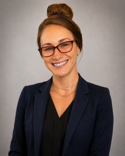Smiling woman with glasses and a bun hairstyle.