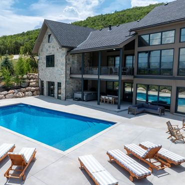 Modern house with a large swimming pool and lounge chairs on a sunny day.