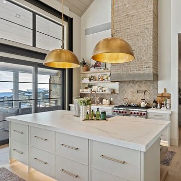 Modern kitchen with large island and gold pendant lights.