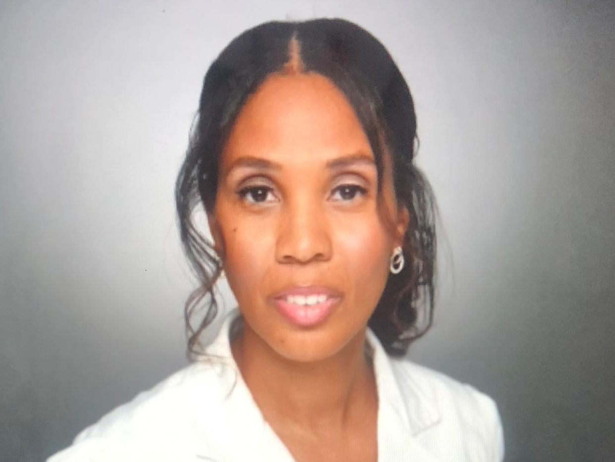 Portrait of a woman with subtle makeup and curled hair wearing a white blazer.