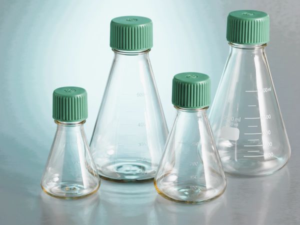 Set of four empty glass Erlenmeyer flasks with green caps.