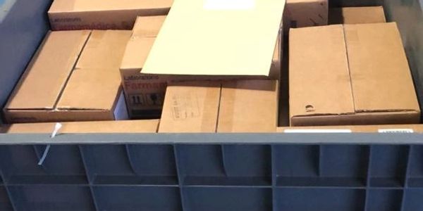 Stacked cardboard boxes inside a large plastic container.