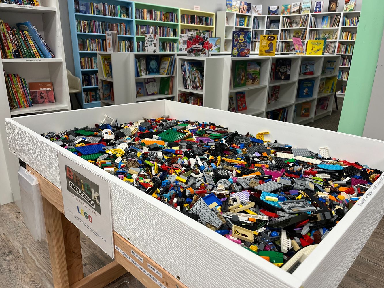 A large white bin filled with colorful LEGO pieces in a bookstore.