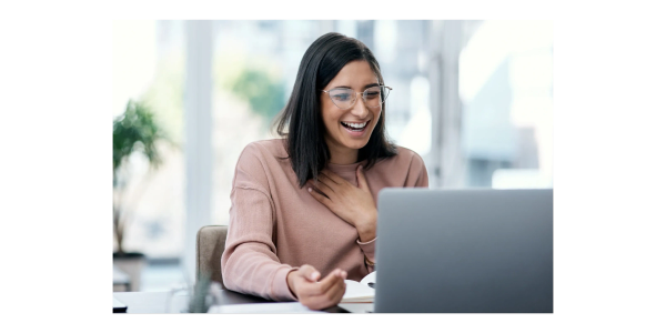 A woman happily laughing while looking at a laptop.