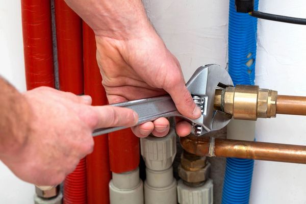 A person holding a wrench and fixing pipes