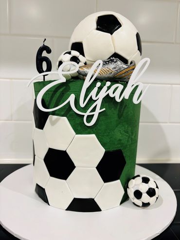 Green soccer-themed birthday cake with name Elijah and number 6 candle.