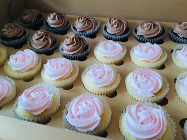 Box of assorted cupcakes with chocolate and pink frosting.