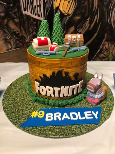 Fortnite-themed birthday cake with game elements and name Bradley.