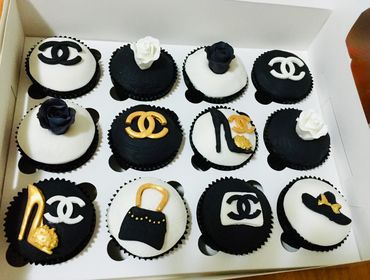 Black and white designer-themed cupcakes with gold accents in a box.