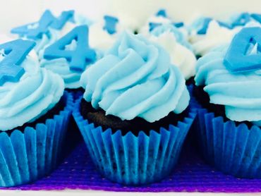 Blue frosted cupcakes with number 4 toppers in blue wrappers.