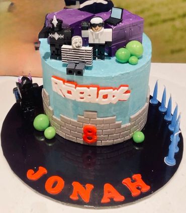 An 8th birthday Roblox-themed cake with character toppers and blue and green decorations.