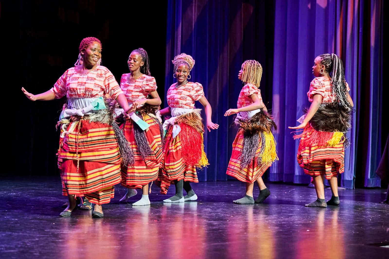 A group of women performing a traditional dance on stage in colorful attire.